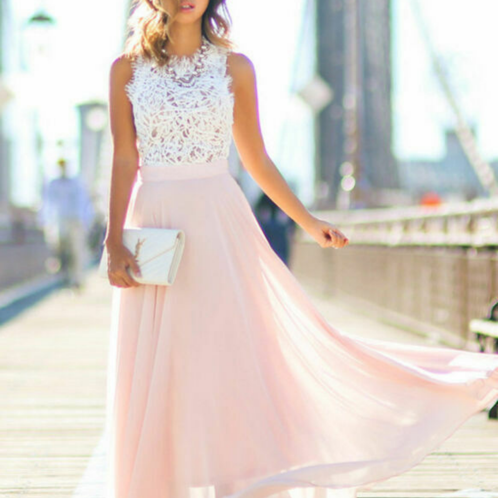 Robe de soirée élégante rose pâle avec haut en dentelle blanche, portée par une femme sur un pont urbain. Mode féminine chic et tendance.