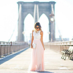 Femme en robe rose pâle sur le pont de Brooklyn, New York, par une journée ensoleillée. Mode élégante, tourisme urbain, architecture iconique.
