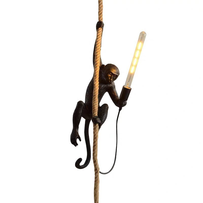 Singe en résine grimpant une corde, tenant une ampoule LED allumée. Lampe design originale, éclairage intérieur, décoration moderne.