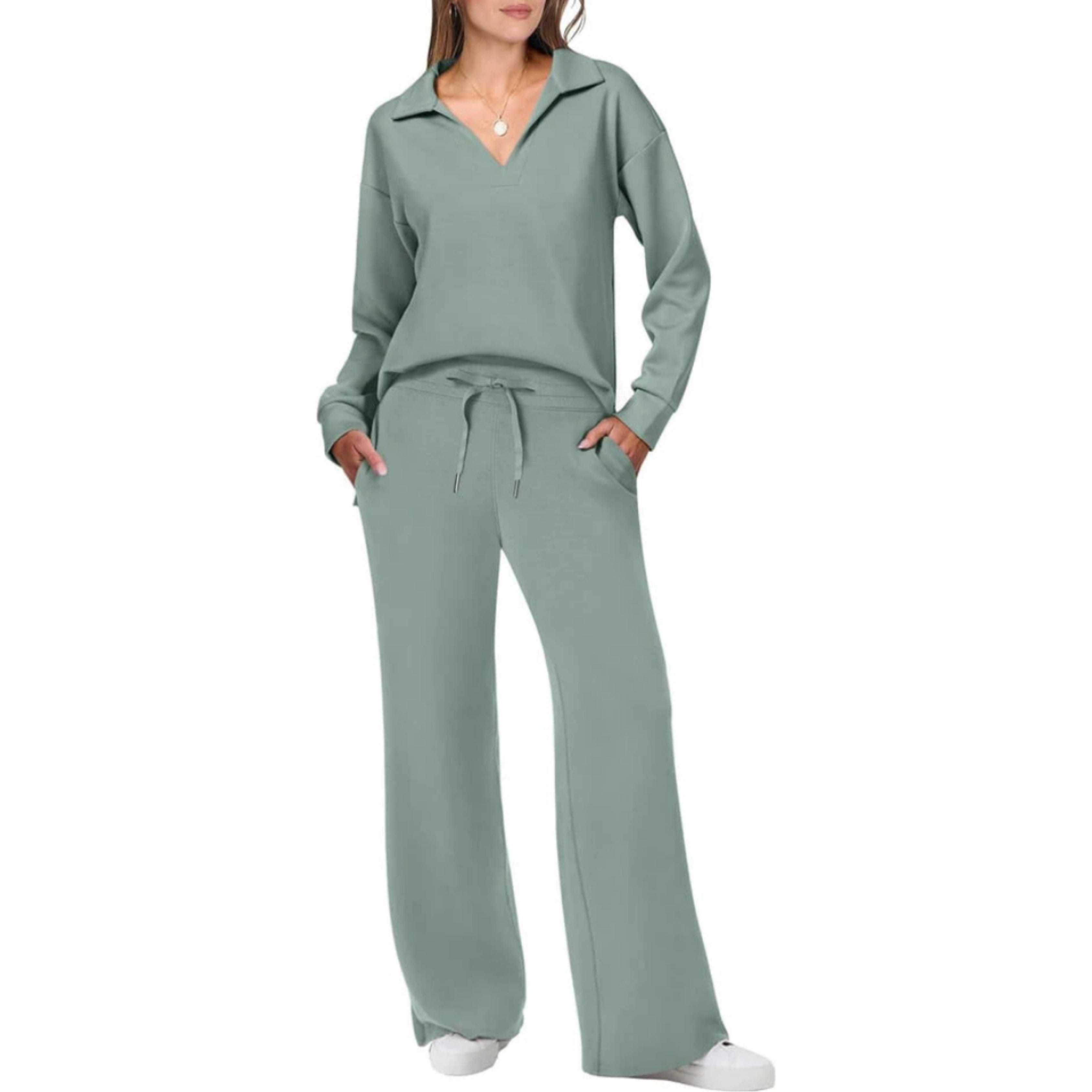 Femme portant un ensemble de survêtement vert menthe, composé d'un pull à col en V et d'un pantalon large, avec des baskets blanches.