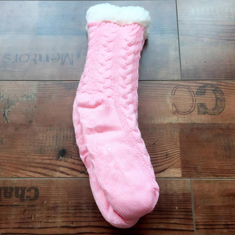 Chaussette rose en tricot avec doublure en fourrure blanche sur parquet en bois. Accessoire d'hiver confortable et chaud.