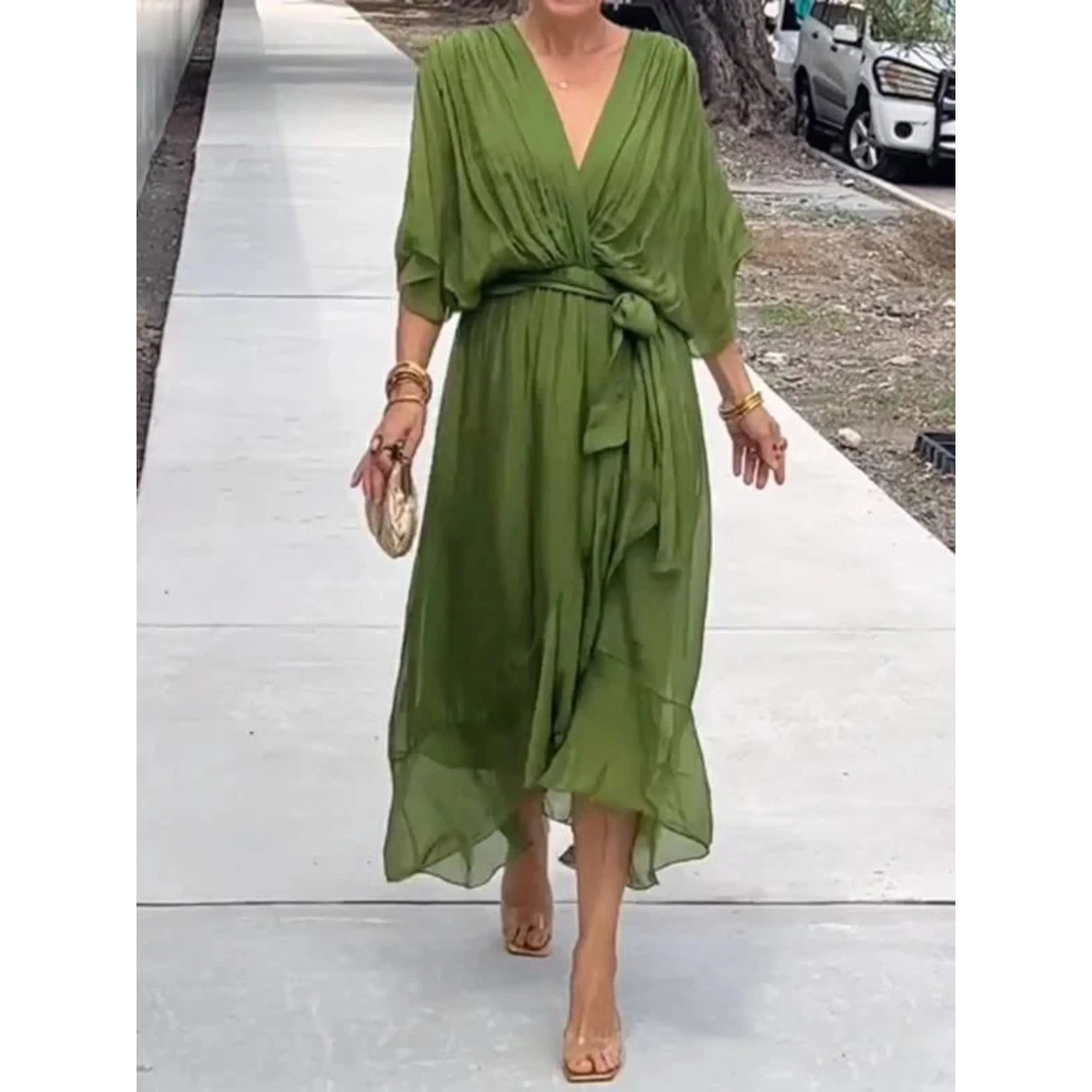Robe longue verte élégante avec ceinture nouée, manches amples, portée par une femme marchant sur un trottoir. Mode féminine chic et tendance.