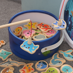 Jeu de pêche magnétique en bois pour enfants, avec canne à pêche et poissons colorés, dans un seau bleu. Jouet éducatif et ludique.