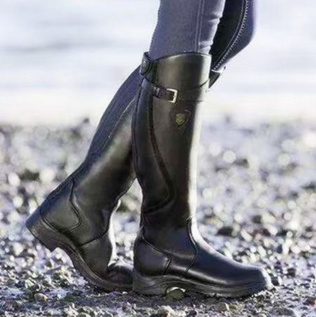 Bottes d'équitation noires en cuir sur galets, style élégant et robuste, idéales pour l'équitation et les activités en plein air.