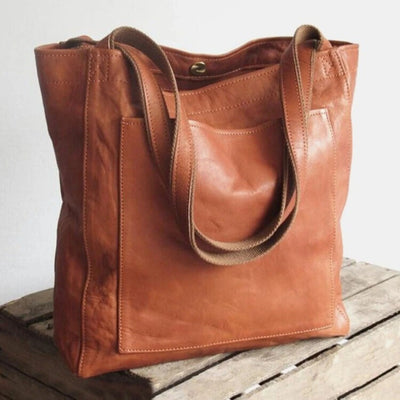 Sac cabas en cuir marron sur une table en bois, design élégant et pratique, idéal pour le quotidien. Accessoire mode tendance et durable.