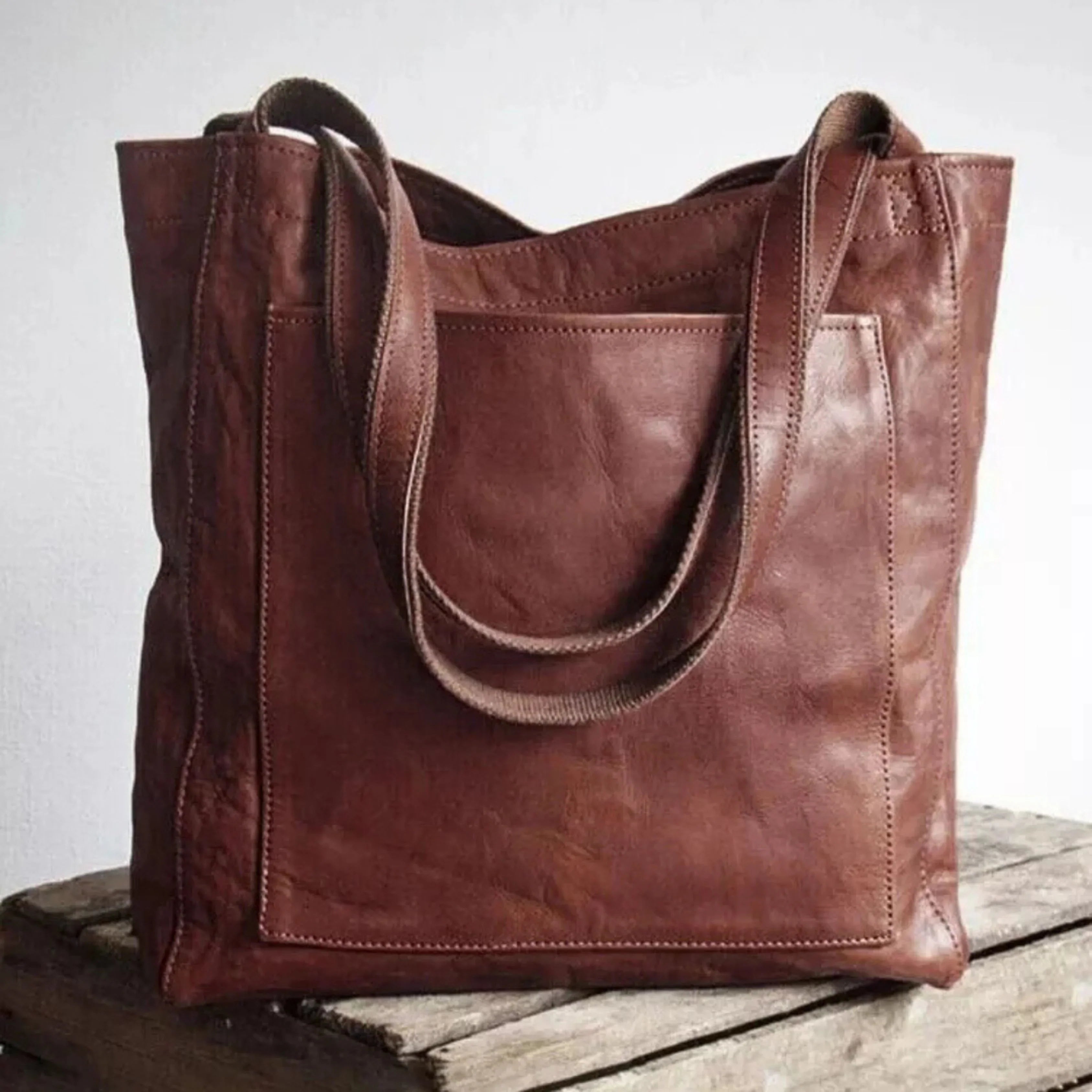 Sac à main en cuir marron sur une table en bois, design élégant et pratique, idéal pour la mode féminine, accessoire tendance et durable.