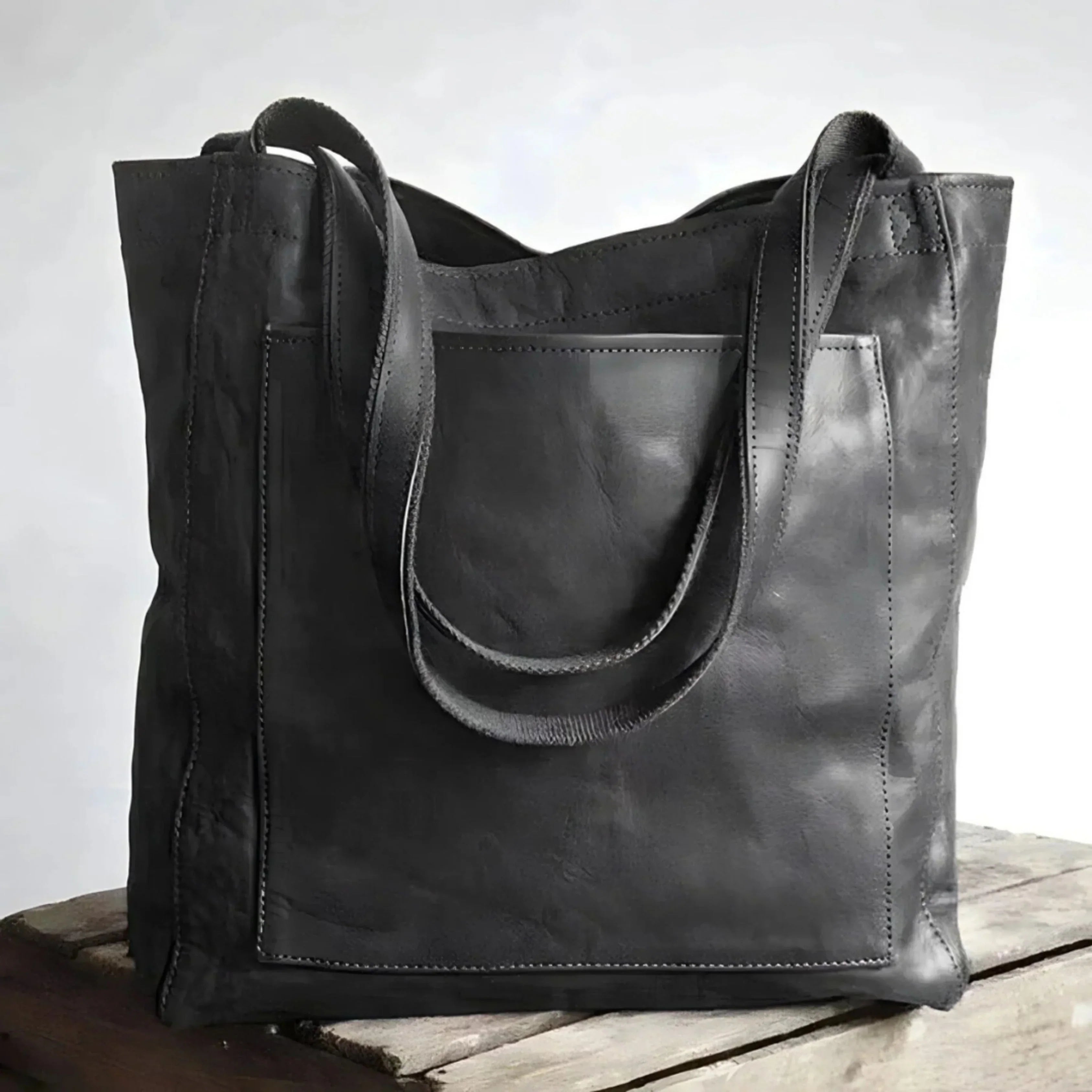 Sac cabas en cuir noir élégant posé sur une table en bois, design moderne et minimaliste, parfait pour la mode urbaine et le shopping.