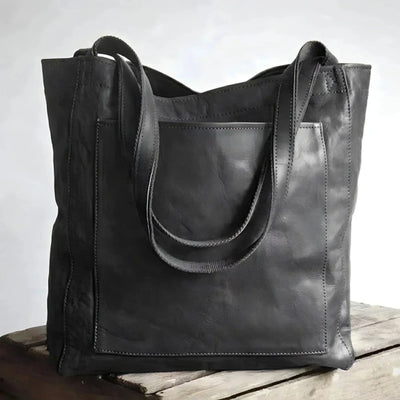Sac cabas en cuir noir élégant posé sur une table en bois, design moderne et minimaliste, parfait pour la mode urbaine et le shopping.