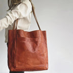Sac en cuir marron porté par une femme en chemise blanche, design élégant et spacieux, idéal pour le shopping ou le bureau. Accessoire mode tendance.