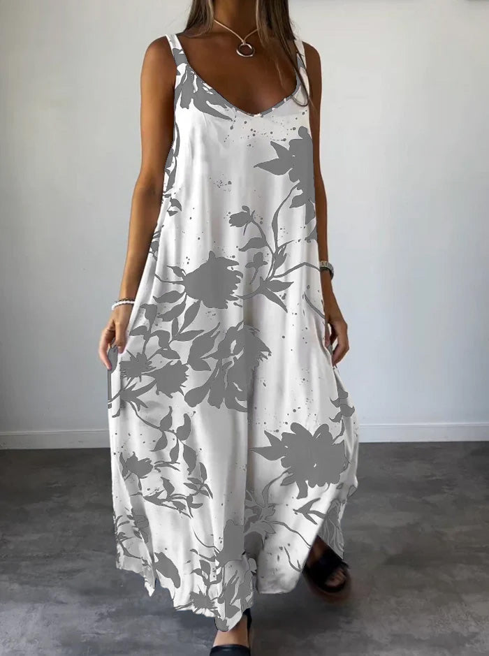 Robe longue d'été blanche à motifs floraux gris, sans manches, portée par une femme. Style décontracté, idéal pour la mode estivale.