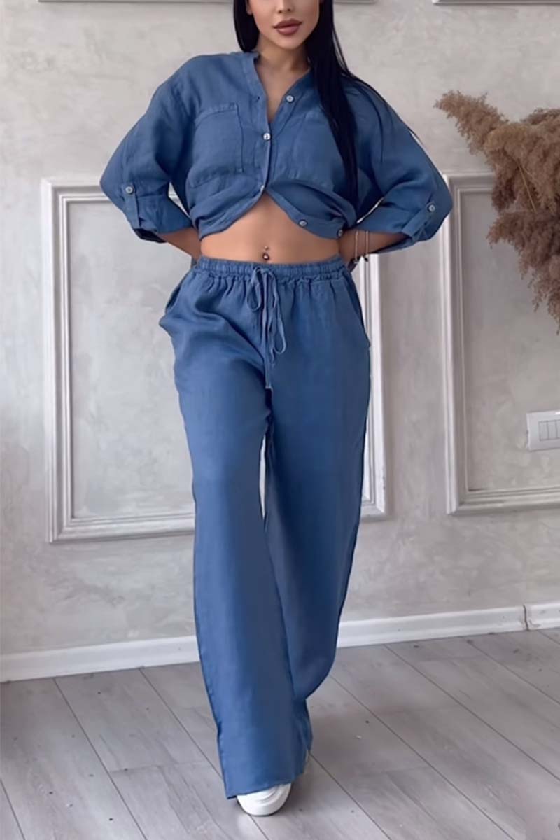 Femme portant un ensemble décontracté bleu, chemise à manches longues et pantalon ample, posant dans un intérieur moderne. Mode tendance, style confortable.