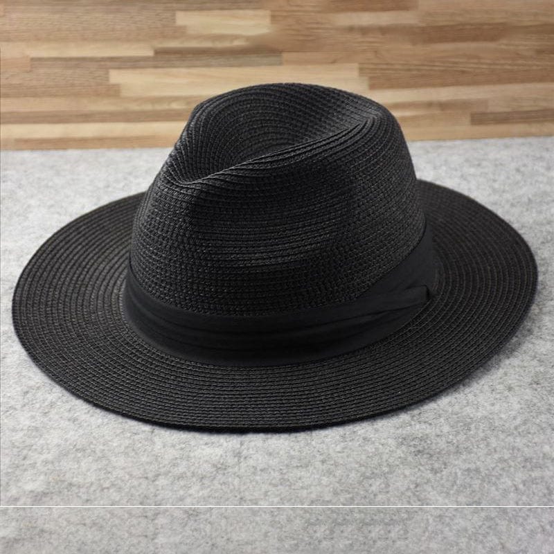 Chapeau Fedora noir en paille tressée sur fond gris, élégant et tendance, idéal pour la mode estivale et les accessoires de style urbain.