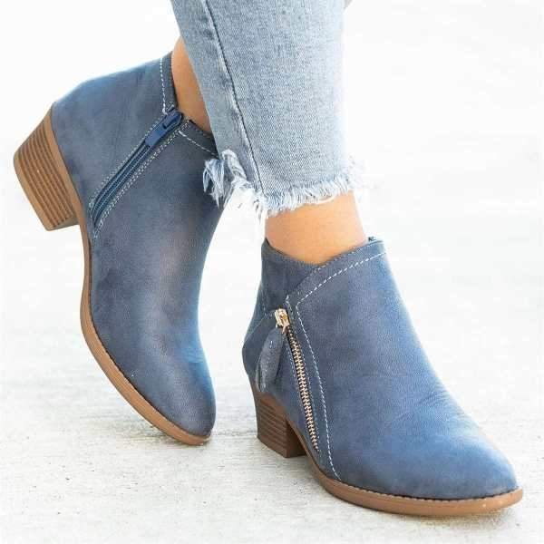 Bottines en cuir bleu pour femme avec fermeture éclair, talon bas, portées avec un jean déchiré. Chaussures tendance automne-hiver.