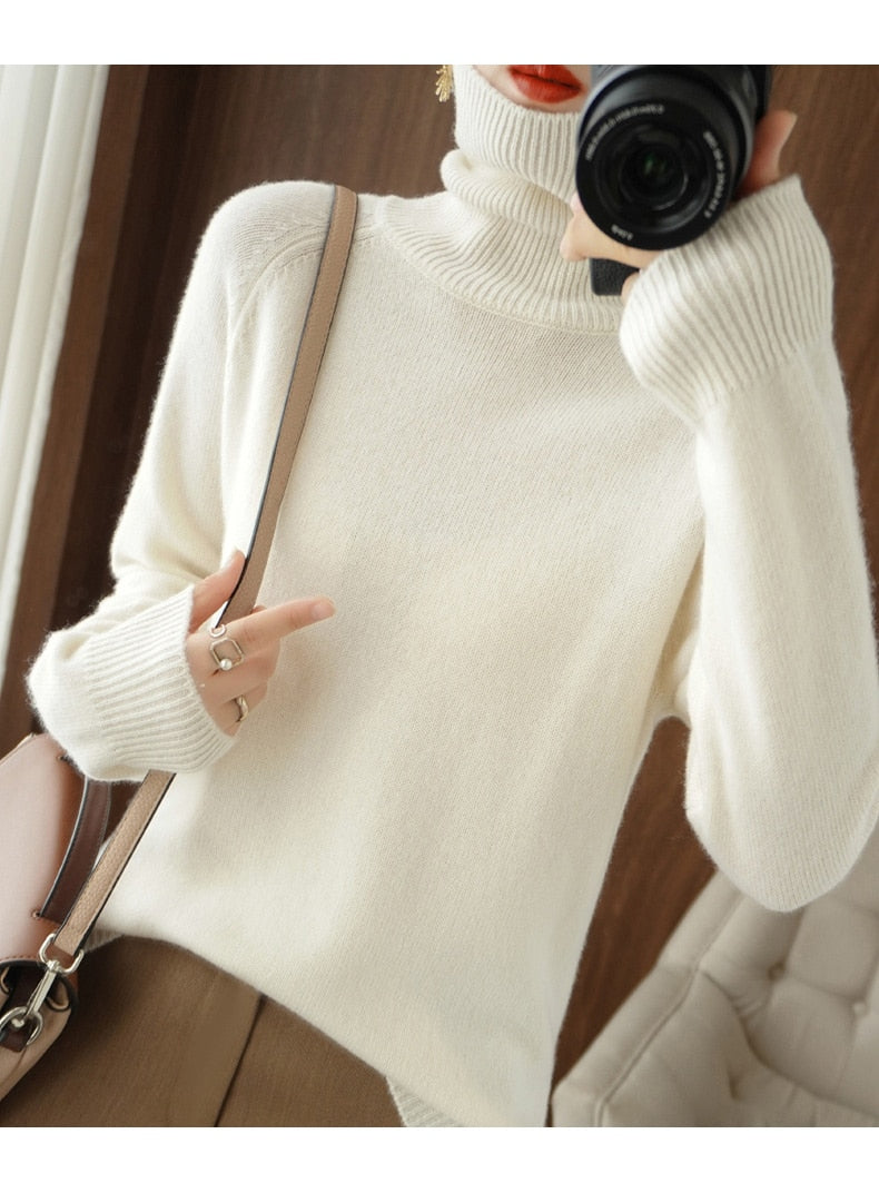 Femme en pull col roulé blanc en laine, tenant un appareil photo. Mode hiver élégante, style décontracté, accessoires tendance.