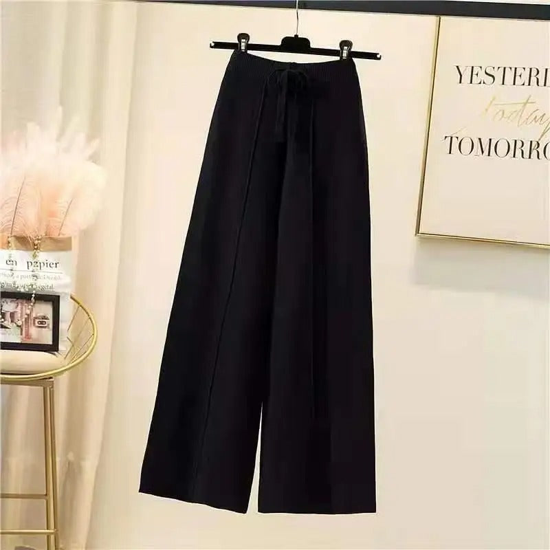 Pantalon large noir suspendu sur un cintre, intérieur moderne avec décoration minimaliste, idéal pour mode féminine élégante et confortable.