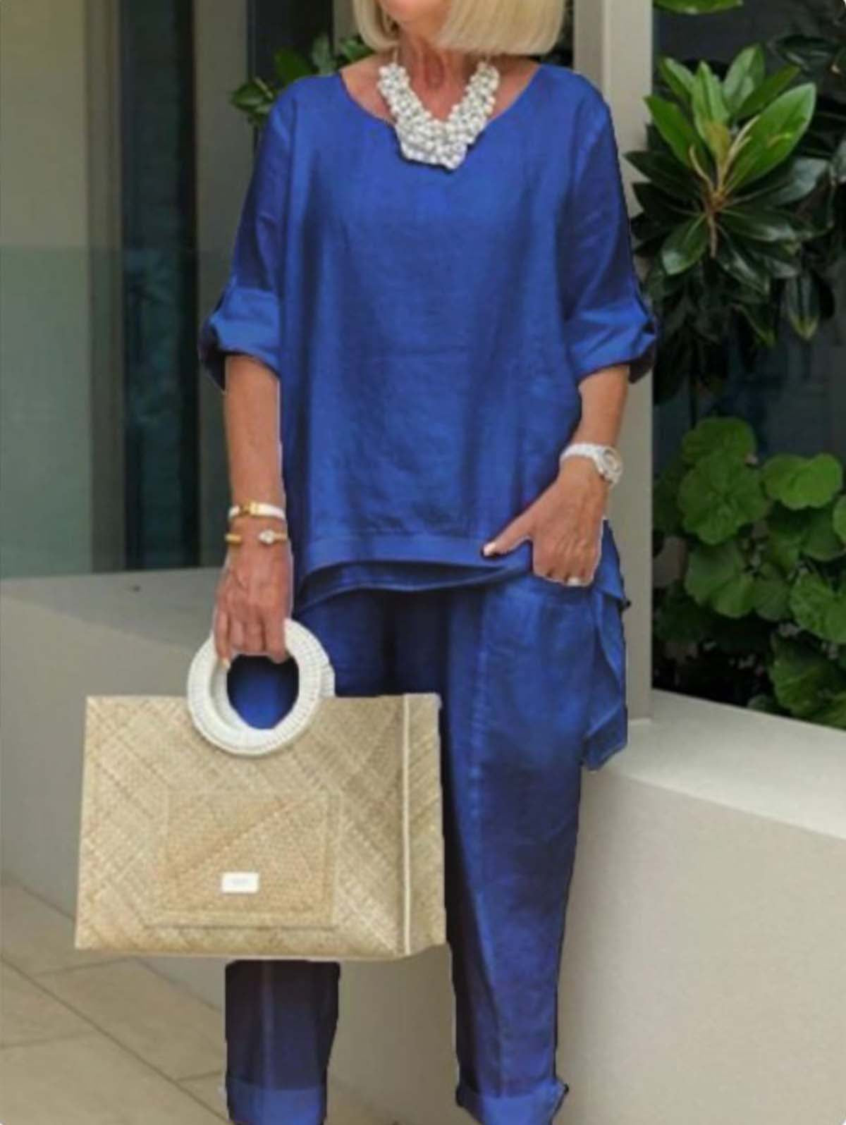 Femme en tenue bleue élégante avec collier perlé, tenant un sac à main en osier. Mode chic, style décontracté, accessoires tendance.