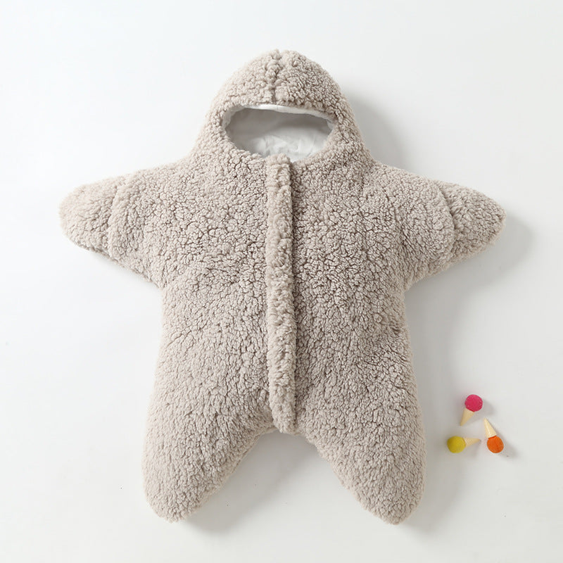 Combinaison bébé en forme d'étoile, en peluche beige, avec capuche. Idéale pour l'hiver, douce et chaude. Accessoire coloré à côté.