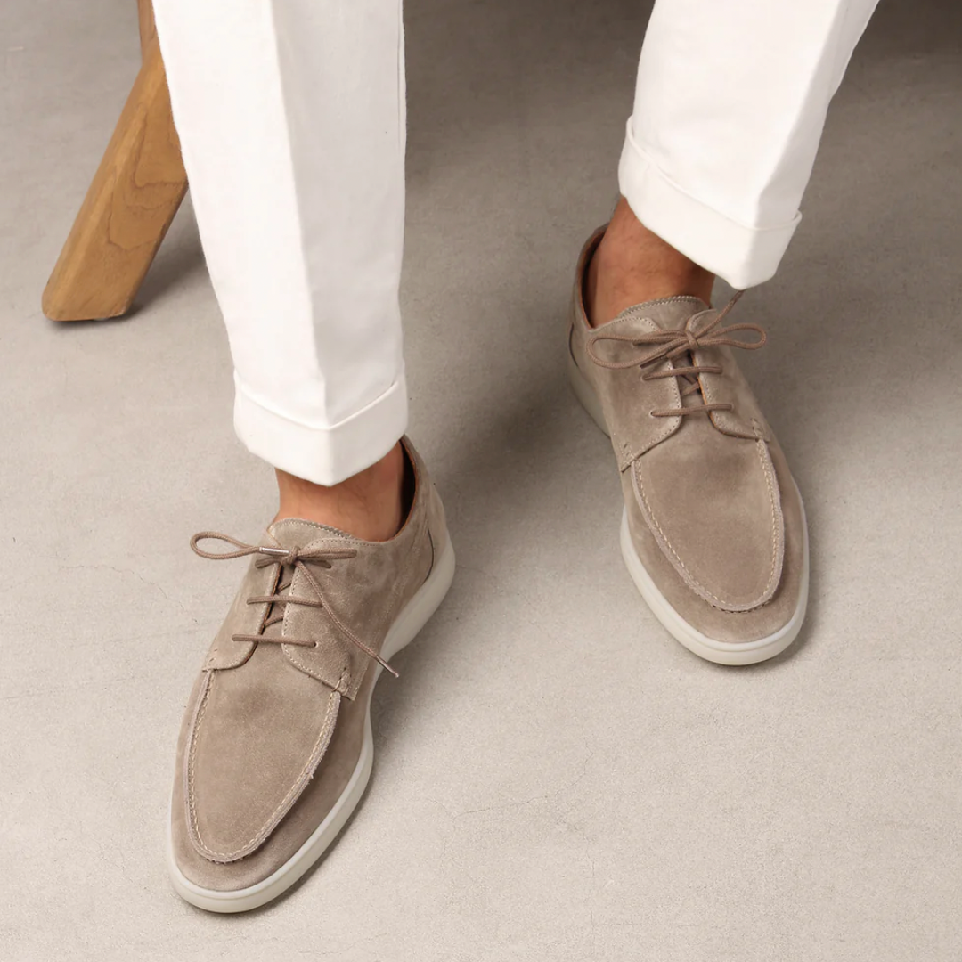 Chaussures derby en daim beige pour homme, élégantes et modernes, portées avec un pantalon blanc. Mode masculine, style décontracté chic.