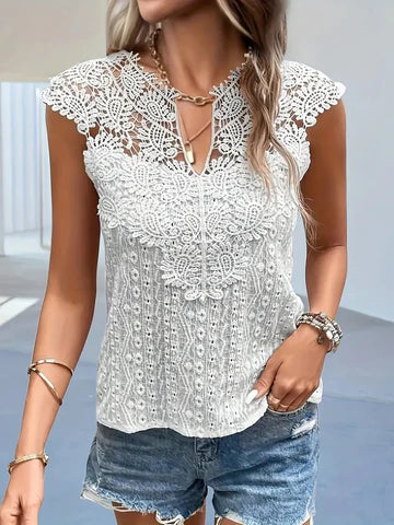 Femme portant un haut en dentelle blanche élégante avec motifs floraux, associée à un short en jean. Mode estivale chic et décontractée.
