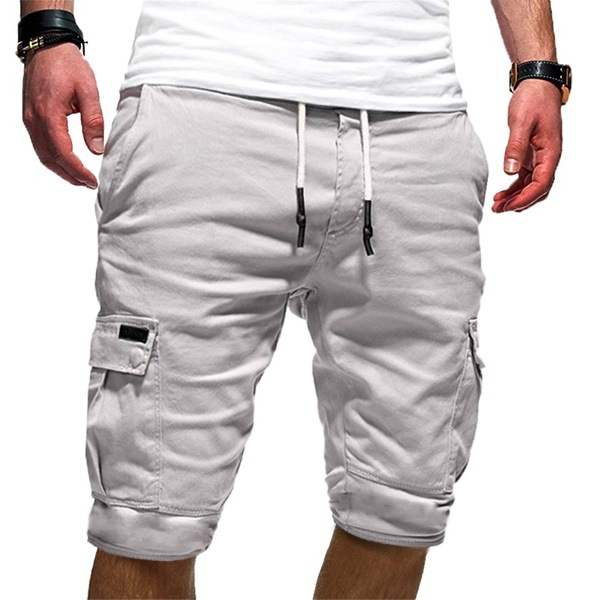 Homme portant un short cargo blanc, style décontracté, avec poches latérales et cordon de serrage, mode estivale masculine.