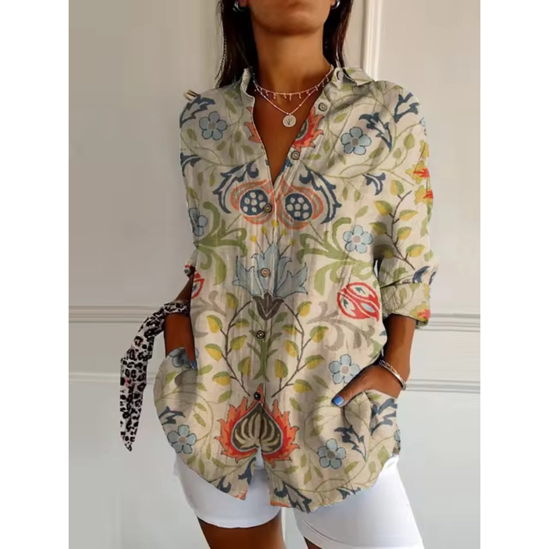 Chemise bohème à motifs floraux colorés, manches longues retroussées, portée par une femme avec short blanc. Mode féminine tendance.
