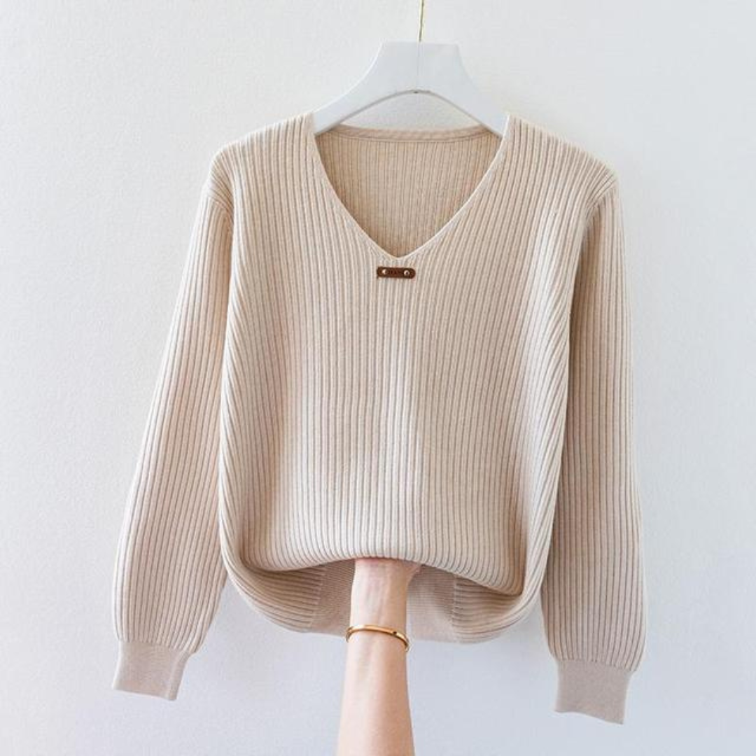 Pull beige en tricot côtelé avec col en V, suspendu sur un cintre blanc. Mode automne, vêtement chaud et élégant pour femme.