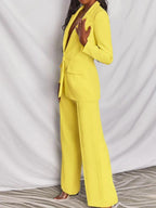 Costume femme jaune vif, élégant et moderne, avec veste cintrée et pantalon large. Mode tendance, tenue professionnelle chic.