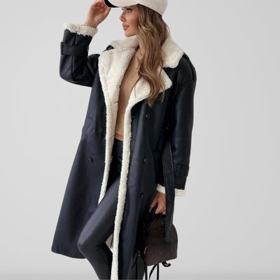 Femme portant un manteau long en cuir noir avec doublure en fourrure blanche, pantalon en cuir noir, casquette beige, sac à main marron. Mode hiver élégante.