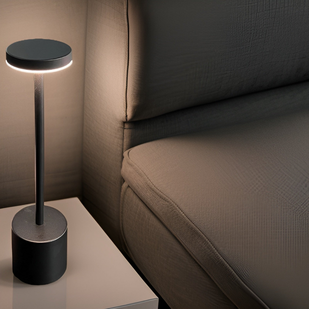 Lampe de chevet moderne noire sur table blanche, éclairant un canapé gris. Design minimaliste, éclairage d'ambiance, décoration intérieure élégante.