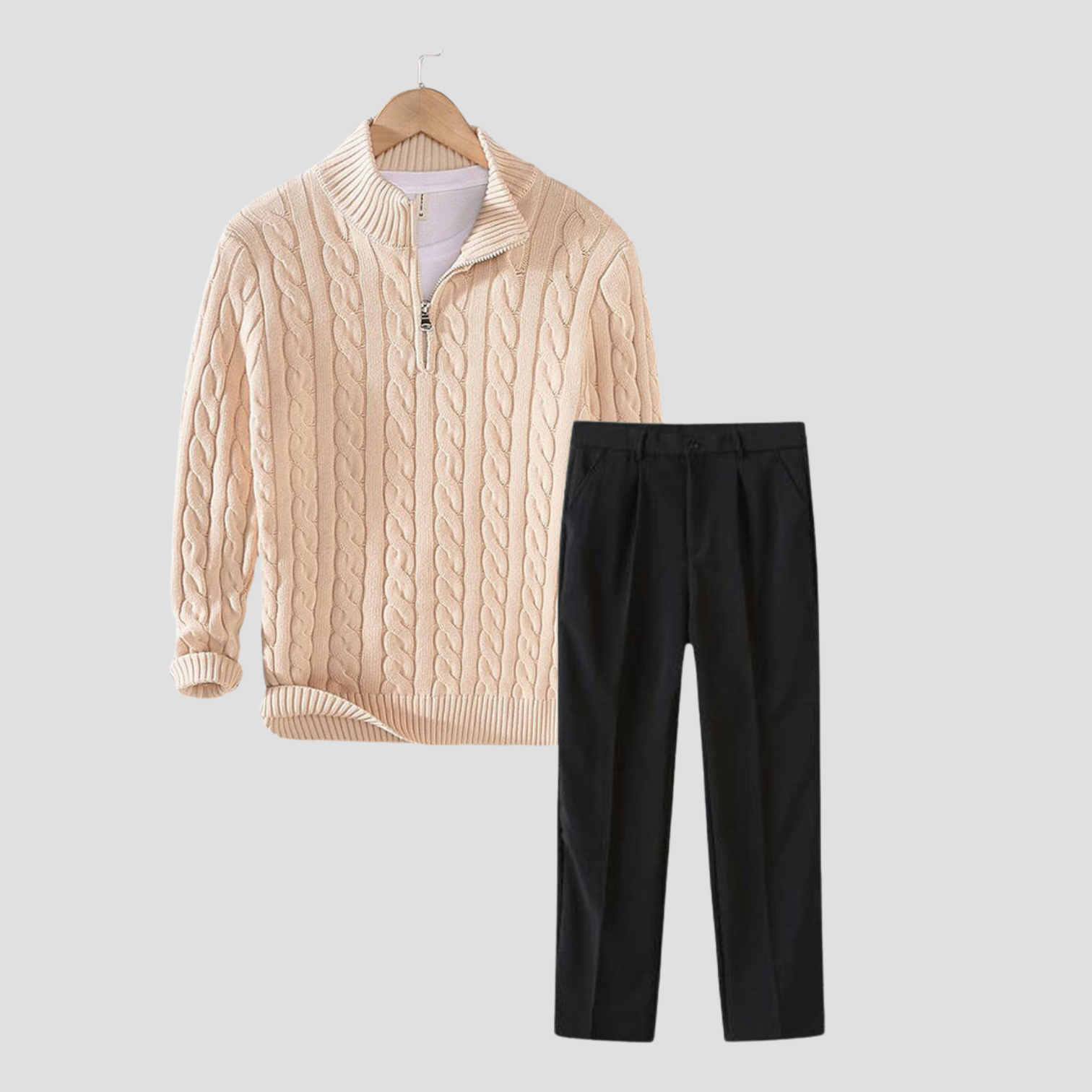 Pull torsadé beige avec fermeture éclair et pantalon noir élégant sur fond gris. Mode automne-hiver, tenue chic et décontractée.