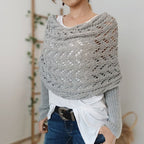 Femme portant un poncho en tricot gris ajouré, style décontracté, sur un t-shirt blanc et un jean. Mode automne-hiver, tendance et confortable.