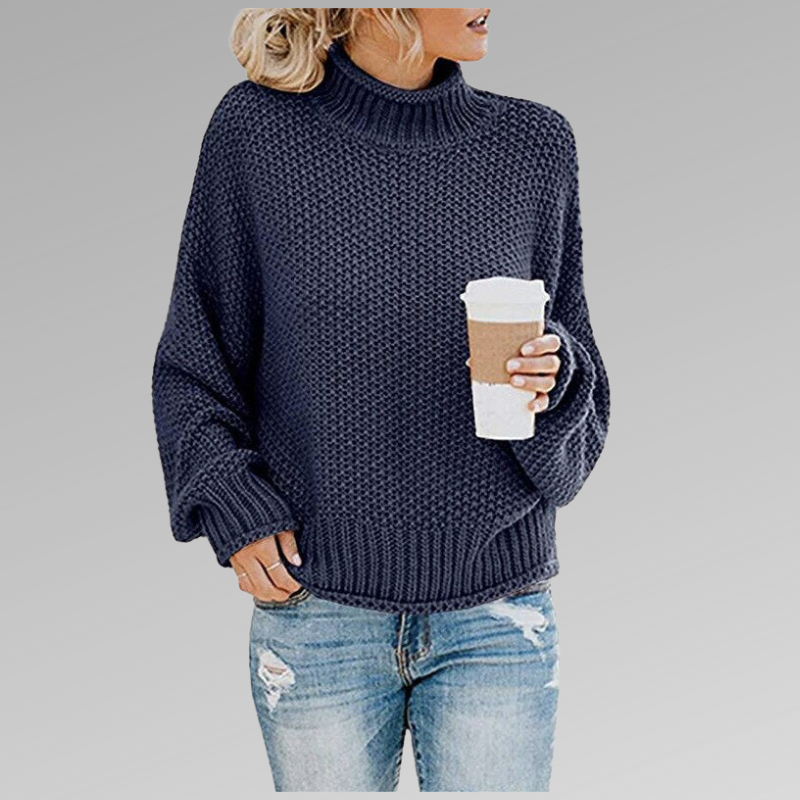 Femme en pull en maille bleu marine, tenant un gobelet de café, portant un jean déchiré. Mode décontractée automne-hiver, style confortable.