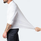 Homme portant une chemise blanche extensible, manches retroussées, tirée par une main; mode masculine, chemise ajustée, tissu élastique.