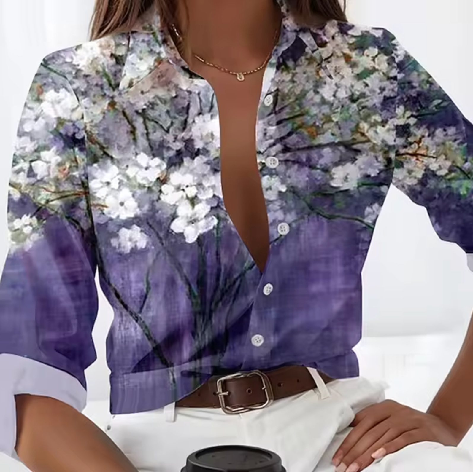 Chemisier femme à manches longues avec motif floral blanc sur fond violet, style décontracté, col ouvert, ceinture marron, mode élégante.