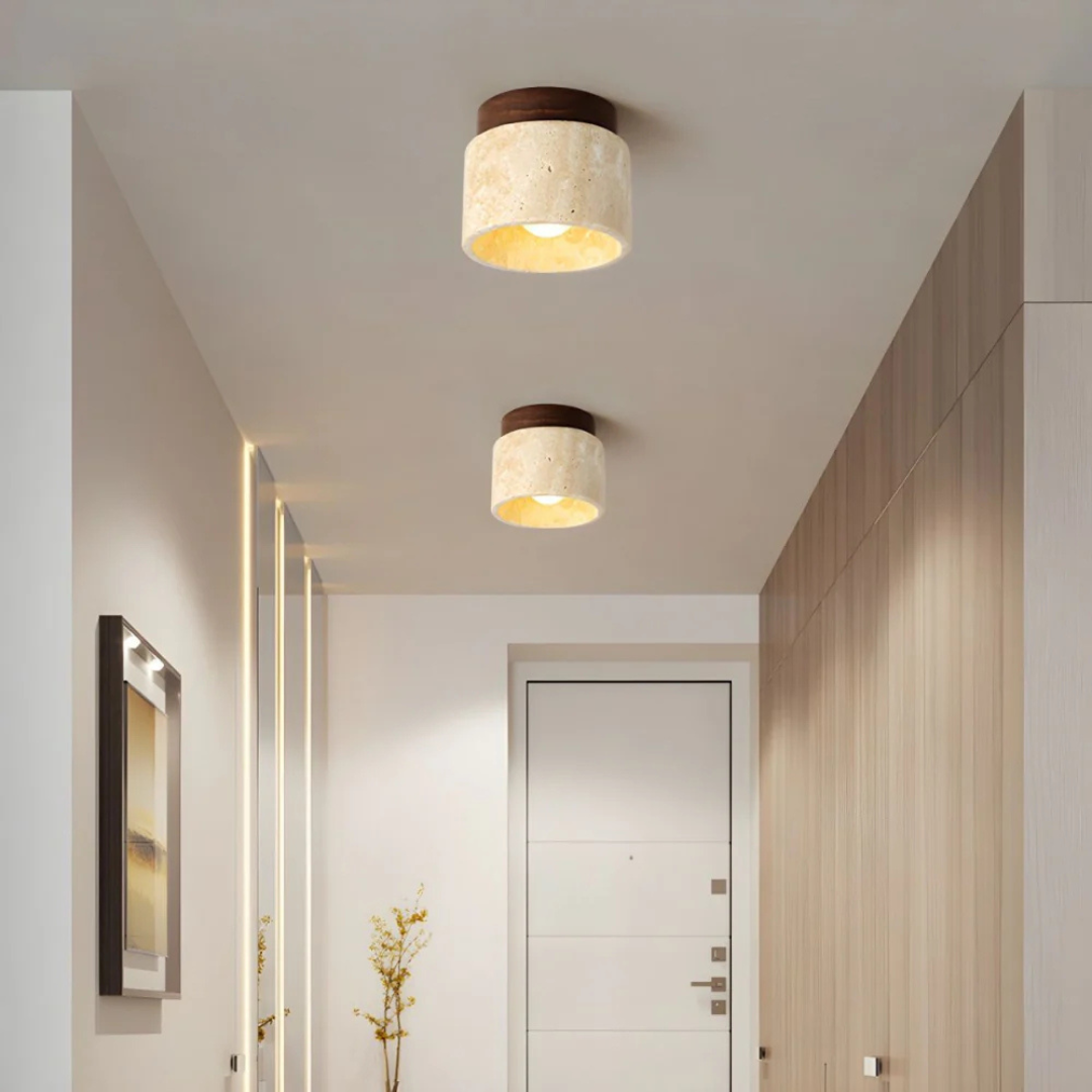 Plafonnier moderne en marbre beige dans un couloir élégant avec porte blanche et murs en bois, éclairage intérieur design contemporain.