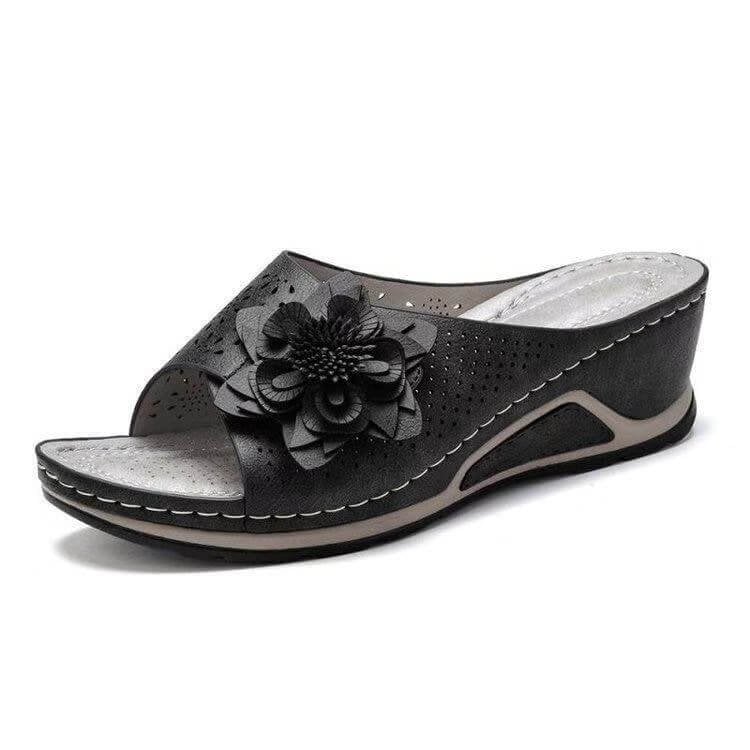 Sandale compensée noire pour femme avec fleur décorative, design élégant et confortable, idéale pour l'été. Chaussure mode tendance.