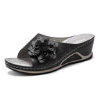 Sandale compensée noire pour femme avec fleur décorative, design élégant et confortable, idéale pour l'été. Chaussure mode tendance.