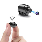 Mini caméra espion sans fil, compacte et portable, tenue entre deux doigts. Idéale pour surveillance discrète, avec connexion Wi-Fi et objectif haute définition.