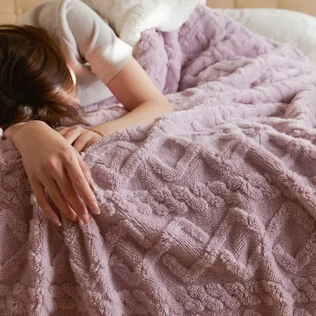Femme endormie sous une couverture en laine rose texturée, lit douillet, ambiance chaleureuse, confort, détente, chambre à coucher.