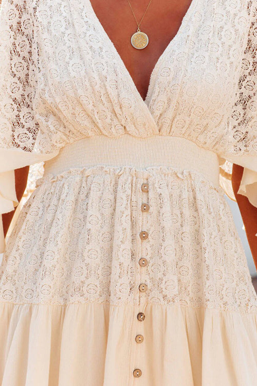 Robe en dentelle blanche avec boutons en bois, col en V profond, manches courtes évasées, ceinture élastique, style bohème chic, mode féminine élégante.
