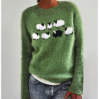 Pull vert en laine avec motif moutons noirs et blancs, manches longues, porté par une personne. Mode automne, style décontracté, tendance tricot.