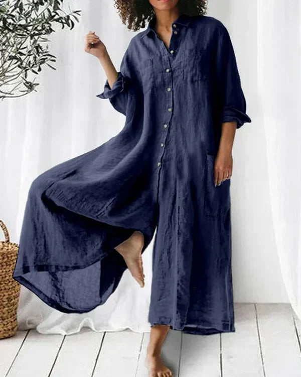 Robe longue en lin bleu marine, manches longues, boutonnée, portée par une femme. Style décontracté, idéal pour l'été. Tissu léger et fluide.