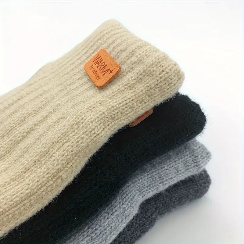 Quatre paires de chaussettes en laine empilées, couleurs beige, noir et gris, étiquette "Warm+" visible, confort et chaleur pour l'hiver.