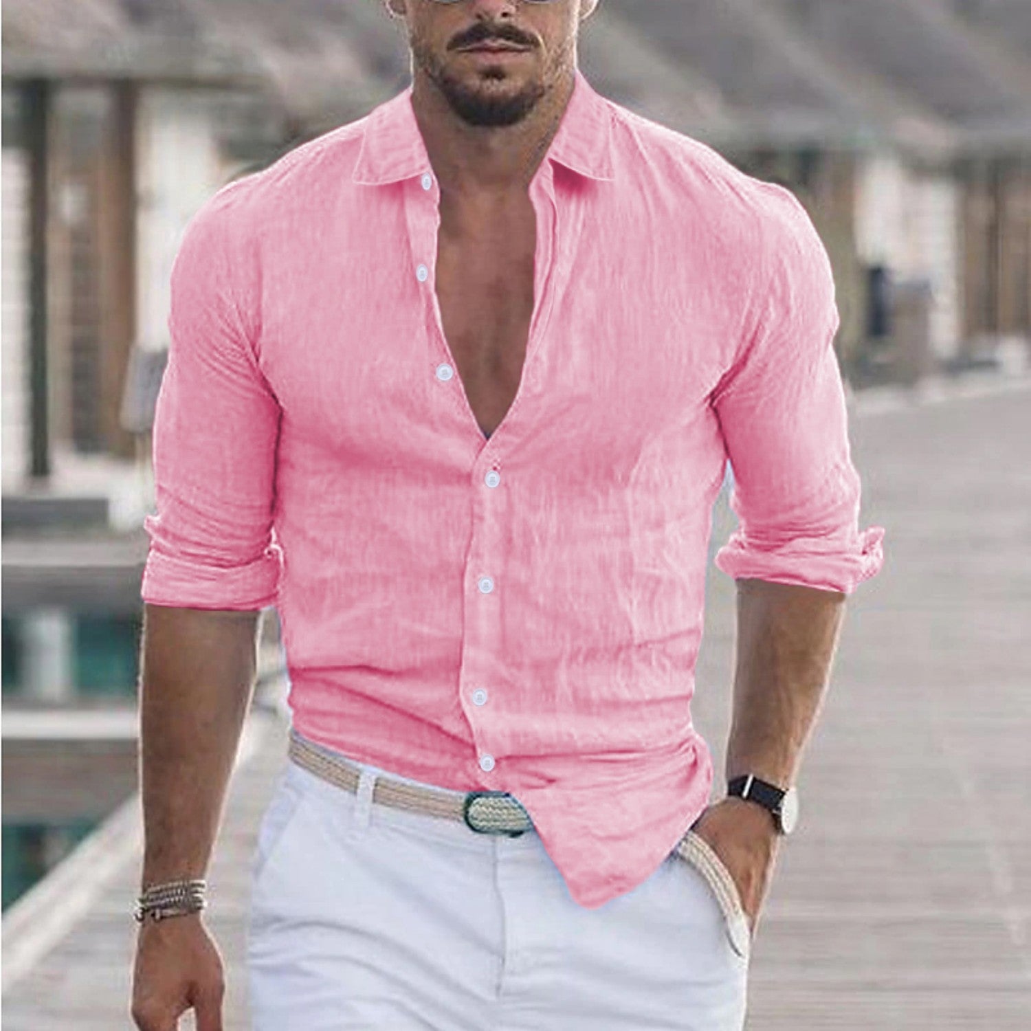 Homme portant une chemise rose en lin, manches retroussées, sur un ponton en bois. Style estival, mode masculine élégante, look décontracté.