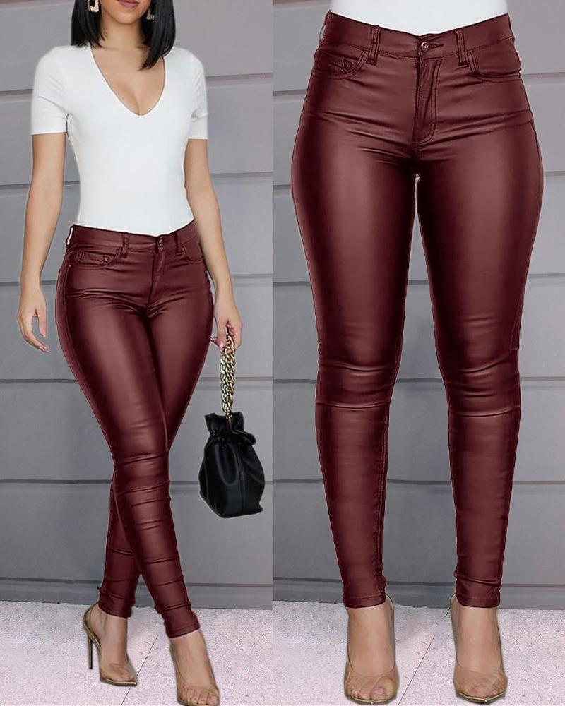 Pantalon en cuir bordeaux pour femme, ajusté et élégant, associé à un haut blanc et des talons nus. Mode féminine tendance et chic.