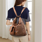 Femme portant un sac à dos en cuir marron avec clous, mode tendance, tenue décontractée, intérieur lumineux, style moderne et chic.