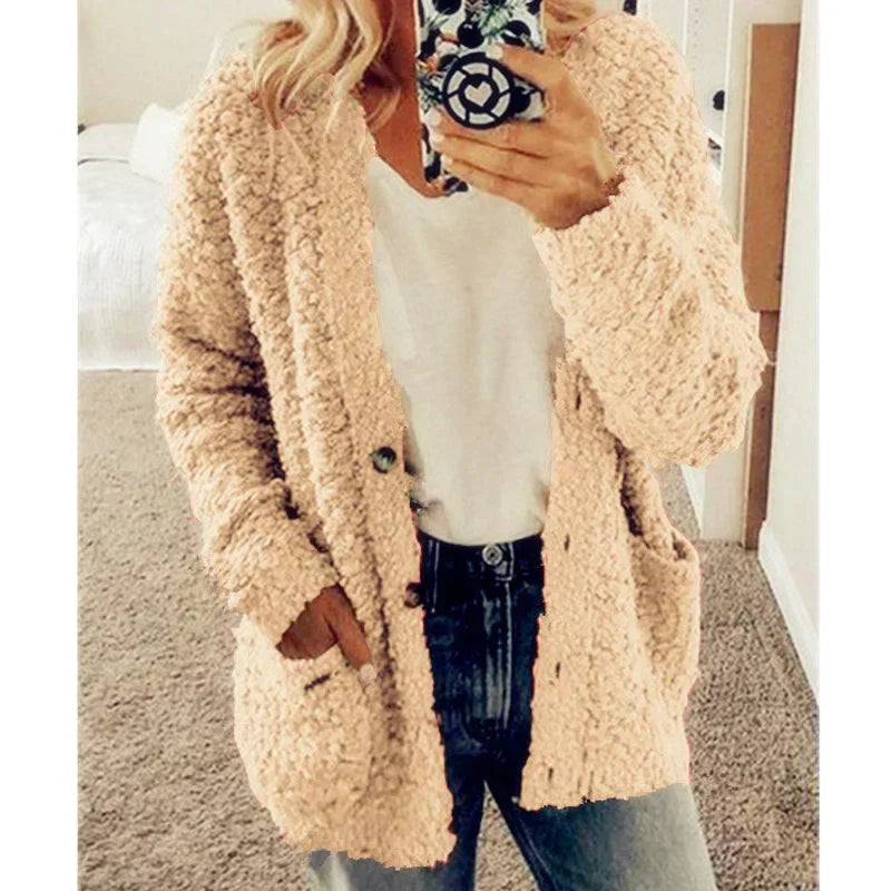 Femme portant un cardigan en laine beige, t-shirt blanc et jean, tenant un smartphone. Mode automne, tenue décontractée, style confortable.
