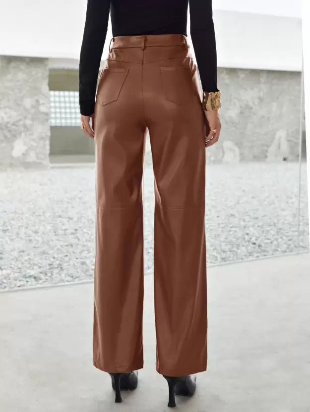 Femme portant un pantalon en cuir marron, vue de dos, avec des talons noirs, dans un espace moderne. Mode élégante, tendance automne-hiver.