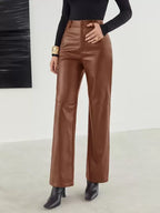 Pantalon en cuir marron pour femme, taille haute, coupe large, porté avec un haut noir à manches longues et des bottines noires, style chic et moderne.
