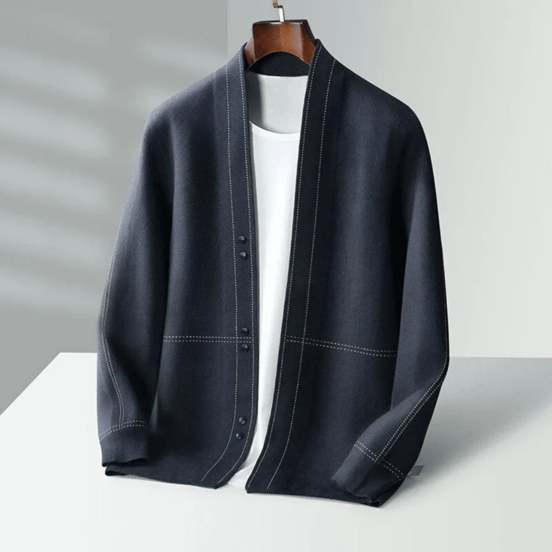 Cardigan noir élégant pour homme sur cintre, avec coutures blanches contrastantes, posé sur fond neutre. Mode masculine, vêtement chic, style moderne.